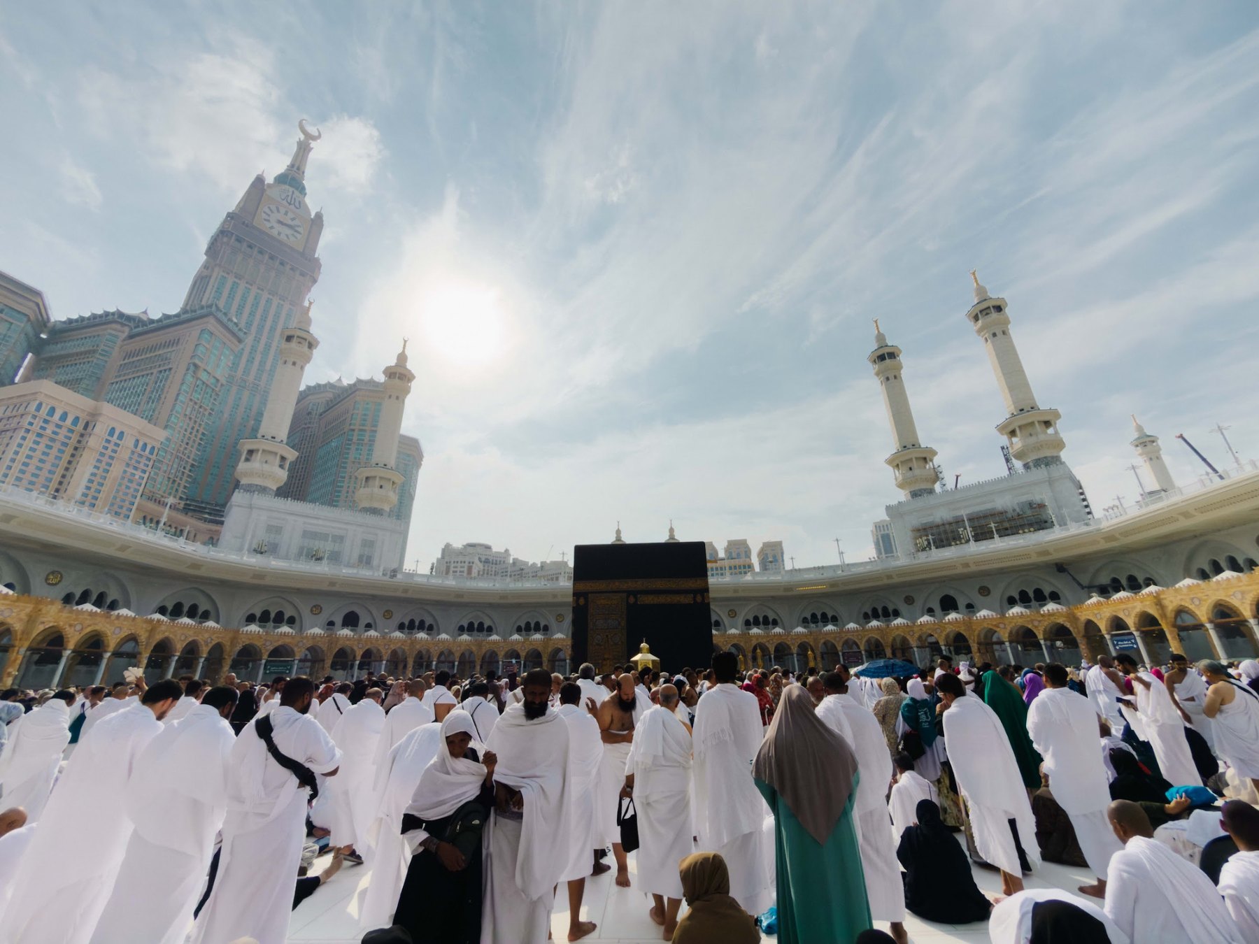 Kaabah dan Masjidil Haram dengan menara jam Makkah, dikelilingi jemaah berihram