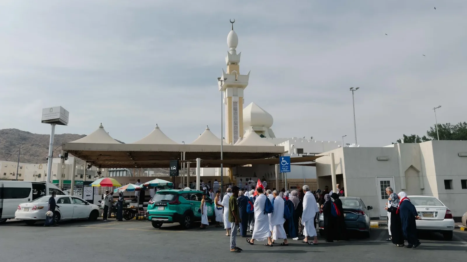 Jemaah berihram di perkarangan Masjid Ji‘ranah dengan menara putih dan payung teduhan
