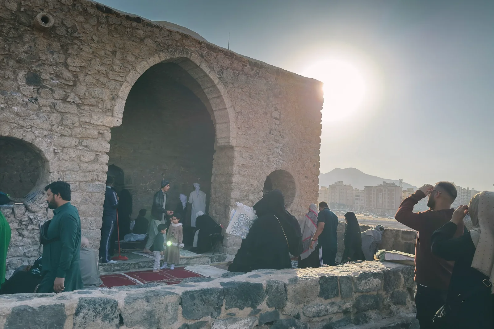Jemaah duduk di hadapan masjid batu lama dalam kawasan Masjid Tujuh di kaki Jabal Sala Madinah pada waktu petang