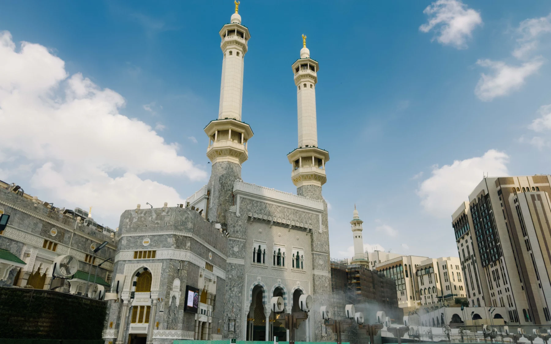 Menara dan pintu Masjidil Haram di bawah langit biru, Mekah
