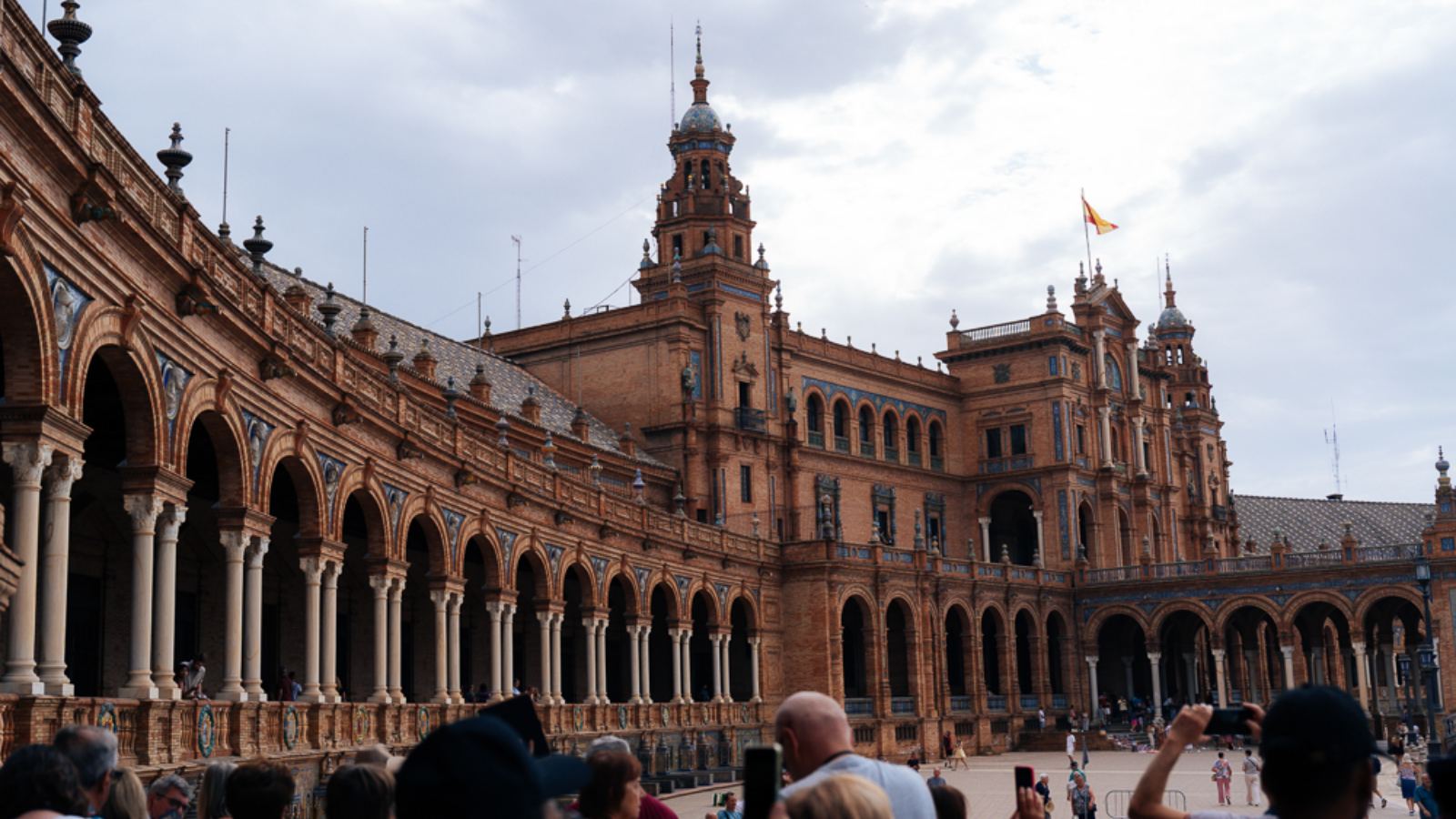 Bangunan separuh bulatan Plaza de España di Sevilla dengan menara dan pengunjung