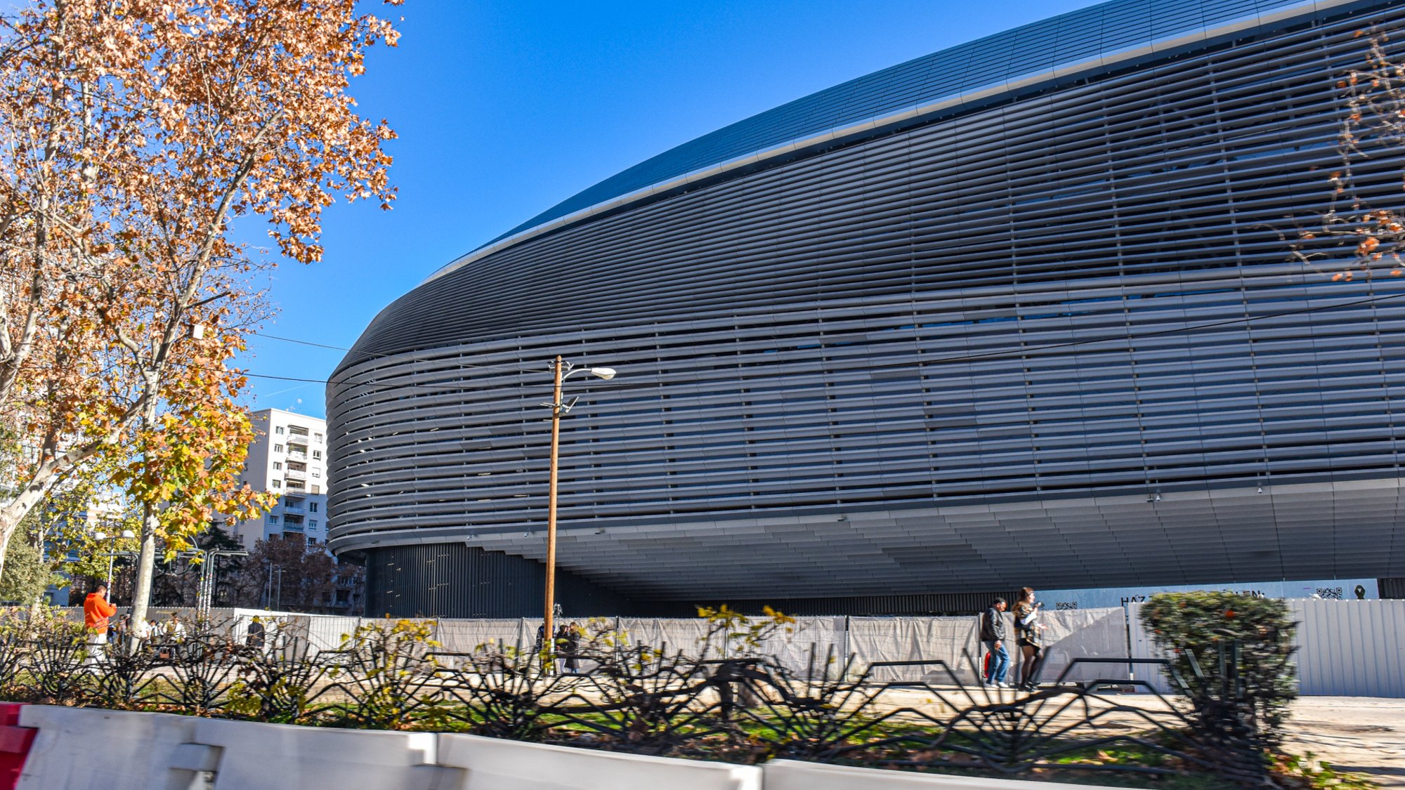 Stadium Santiago Bernabéu dengan fasad keluli dan pokok musim luruh di Paseo de la Castellana
