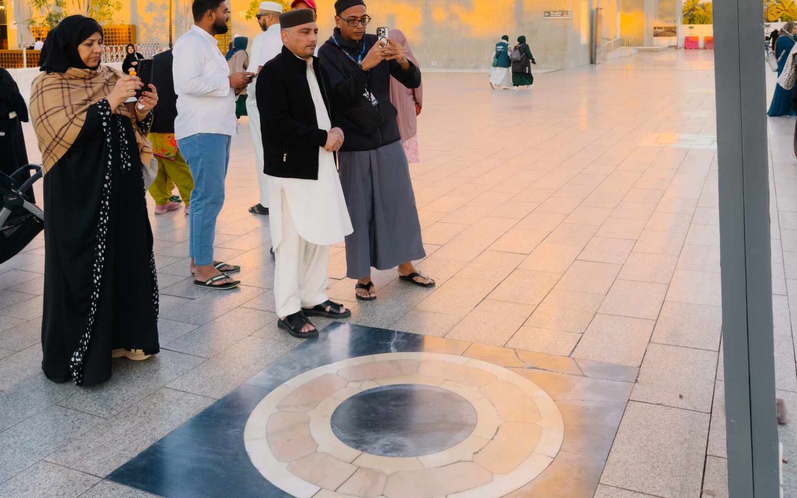 Pengunjung di penanda bulat tapak Telaga Aris, dataran Masjid Quba