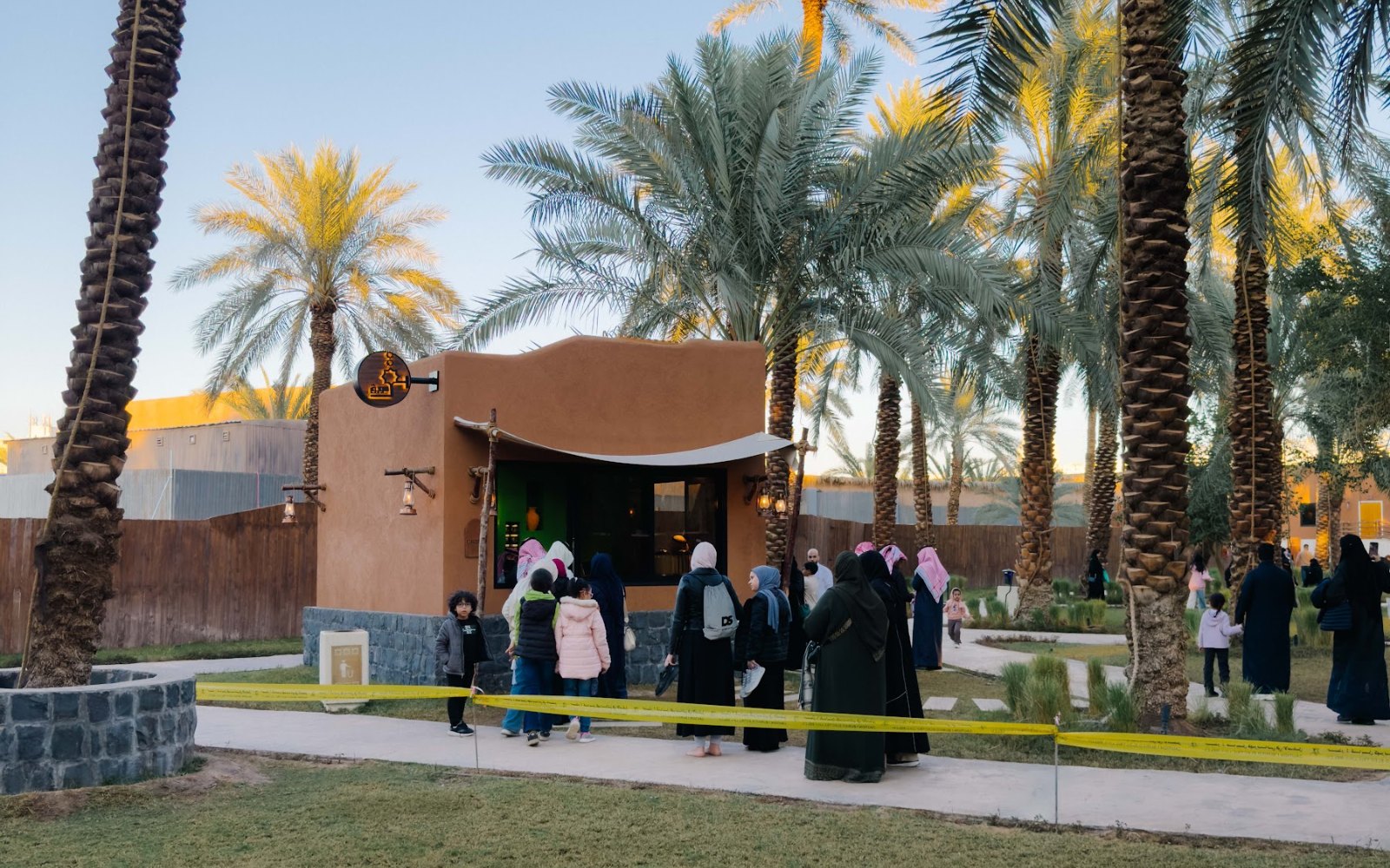 Deretan pohon kurma dan pondok kayu di sebuah taman warisan di kawasan Quba, Madinah