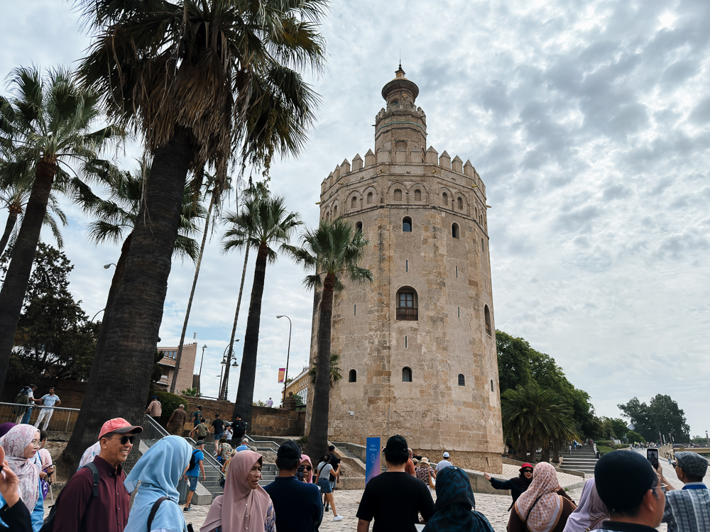 Rombongan pelawat di hadapan Torre del Oro, menara Almohad di tebing Sungai Guadalquivir
