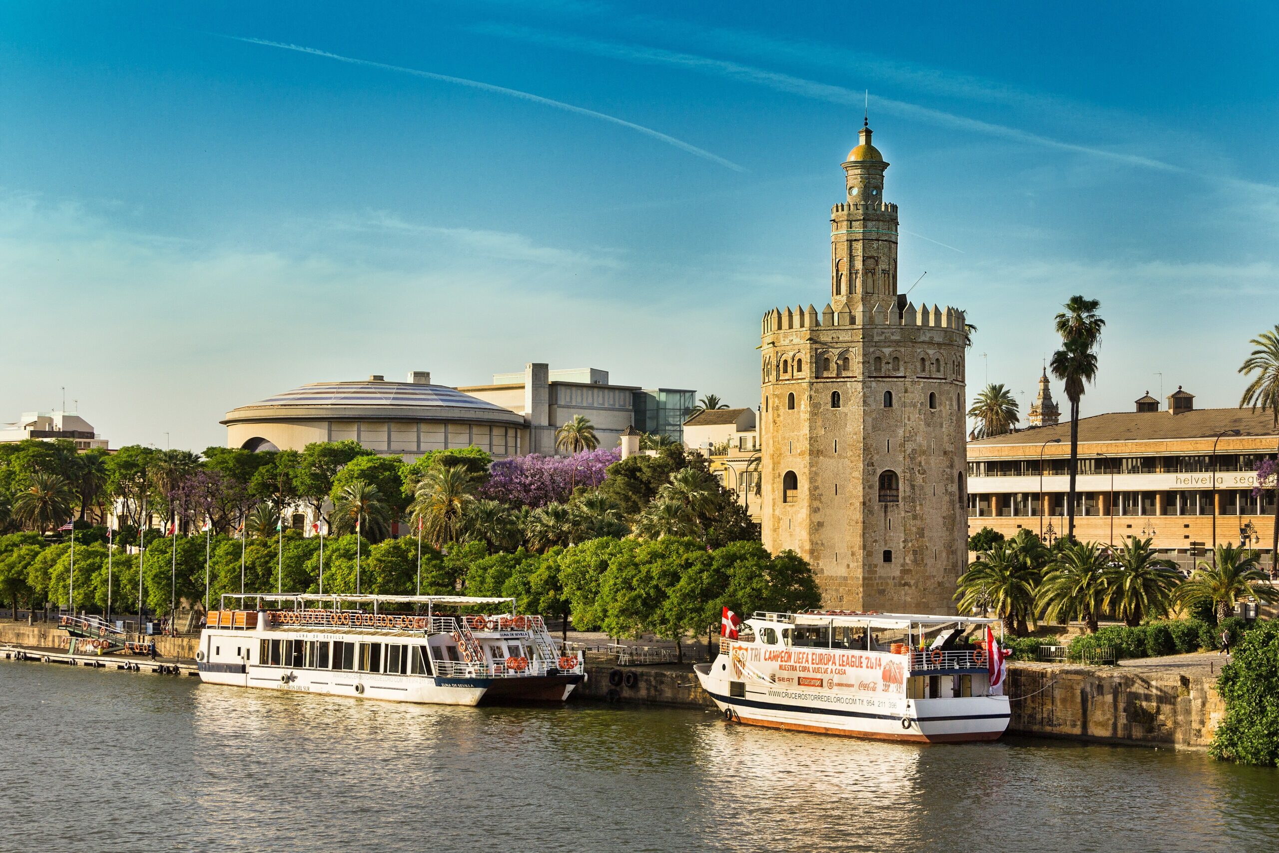 Torre del Oro di tebing Sungai Guadalquivir dengan bot pelancong di hadapannya